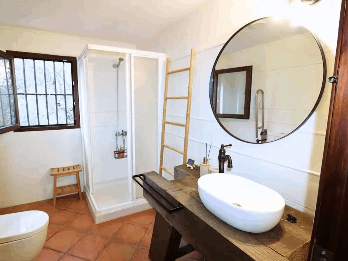 Baño con ducha, mampara de cristal y lavabo de obra