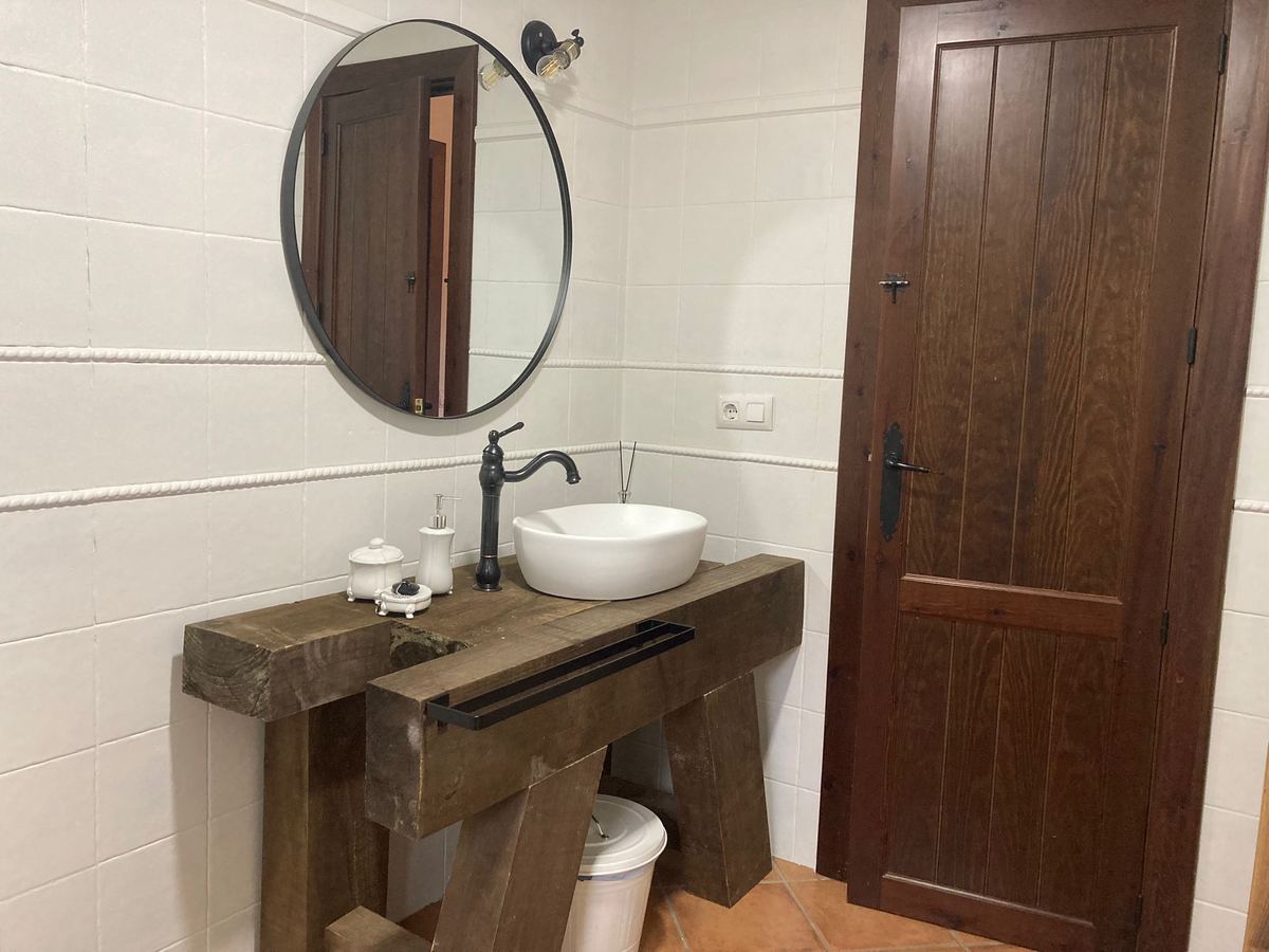 Baño con lavabo sobre encimera de madera y espejo redondo