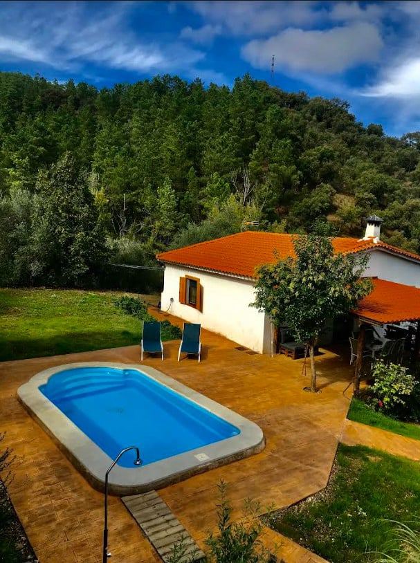 La casa y la piscina vistas desde el aire, rodeadas de arbolado