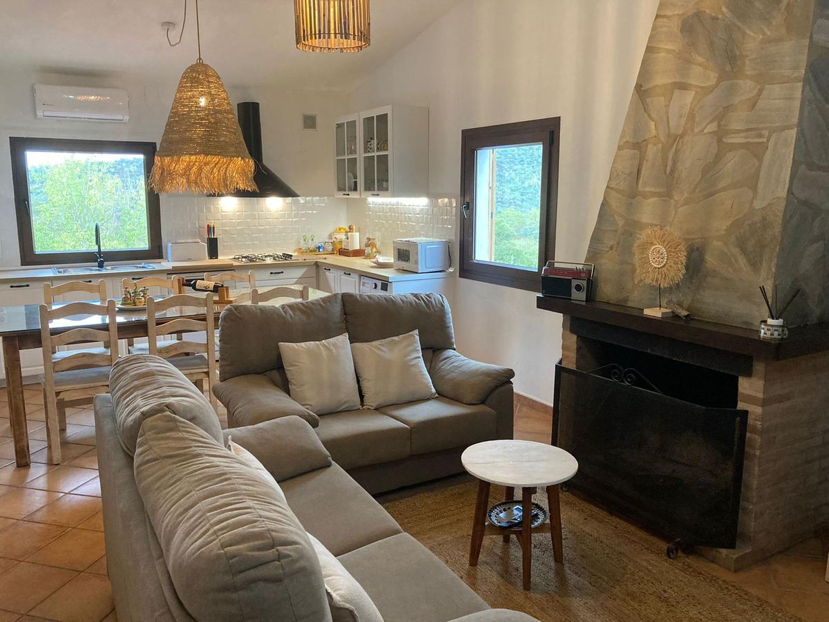 Salón con sofás y chimenea, abierto a la zona de cocina