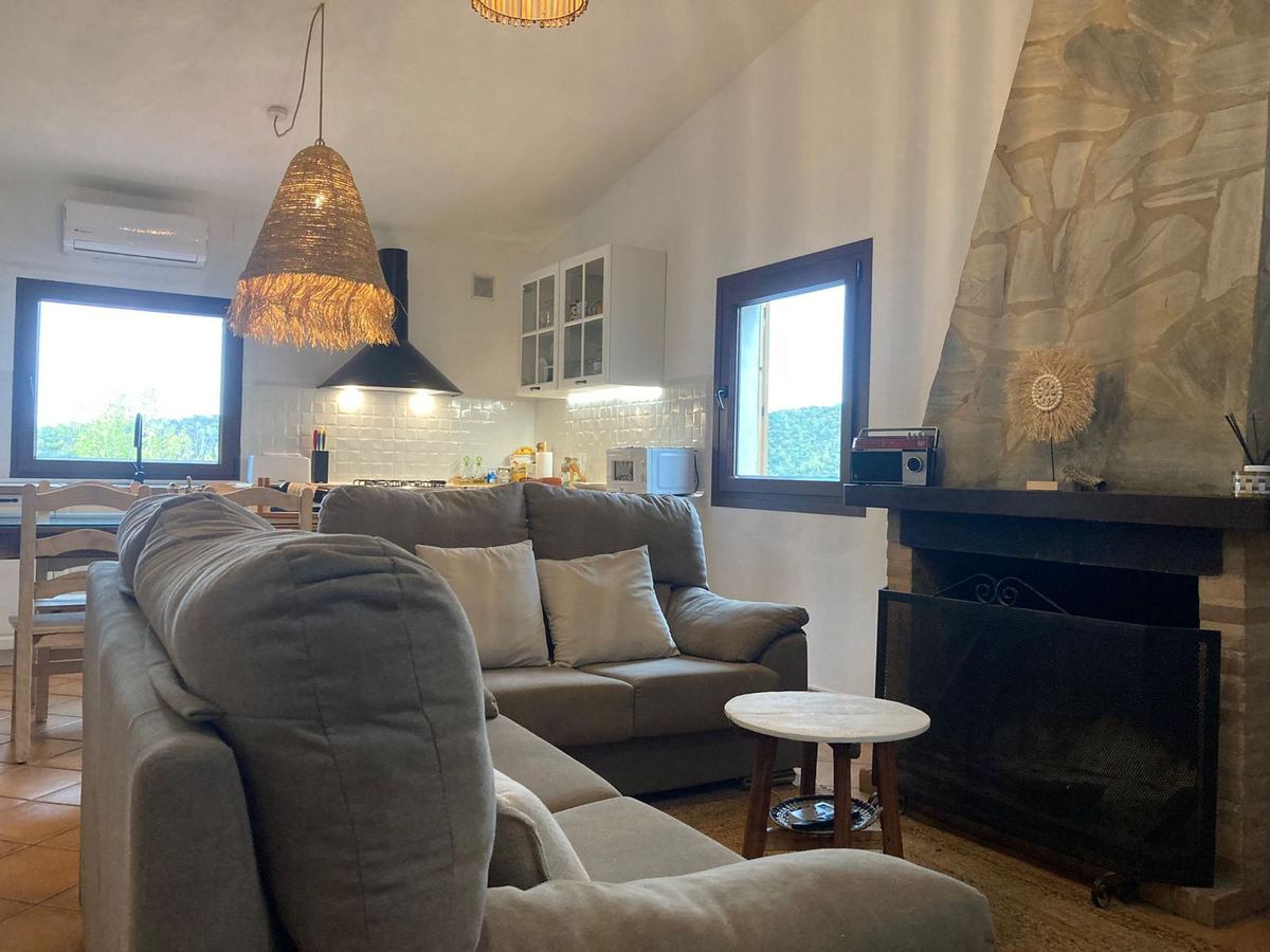 Sofás del salón junto a la chimenea, con la cocina al fondo