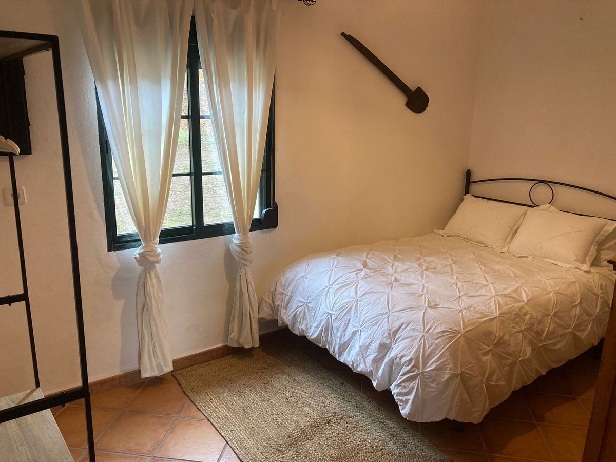 Dormitorio con cama de matrimonio y ventana con cortinas