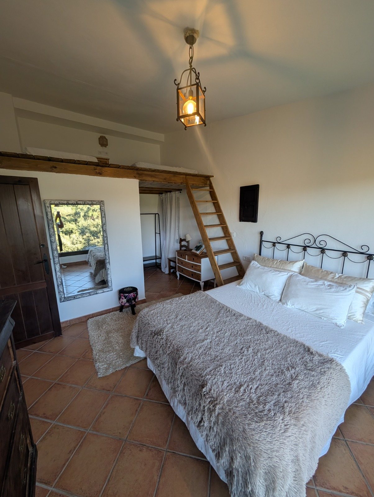 Habitación del ventanal, con cama de matrimonio y la escalera de madera que sube al altillo
